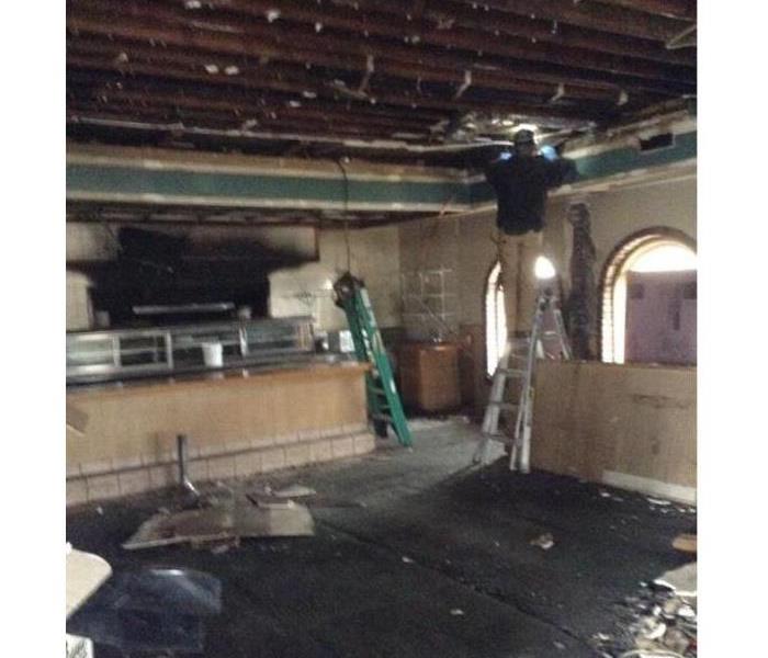 A restaurant with apparent fire damage and ripped out ceiling. SERVPRO workers are present 